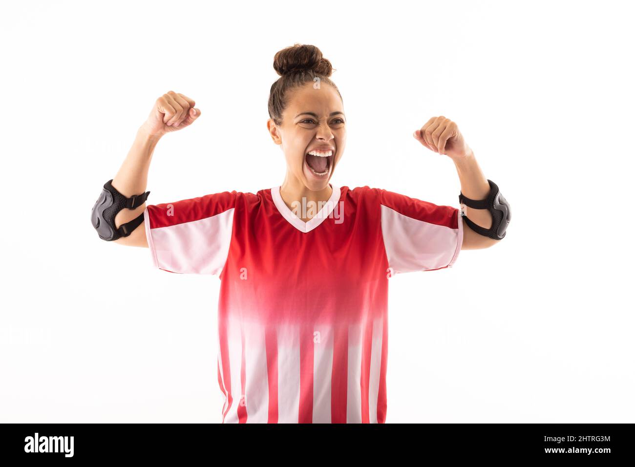 Fröhliche biracial junge weibliche Handballspielerin mit geballter Faust, die vor weißem Hintergrund schreit Stockfoto
