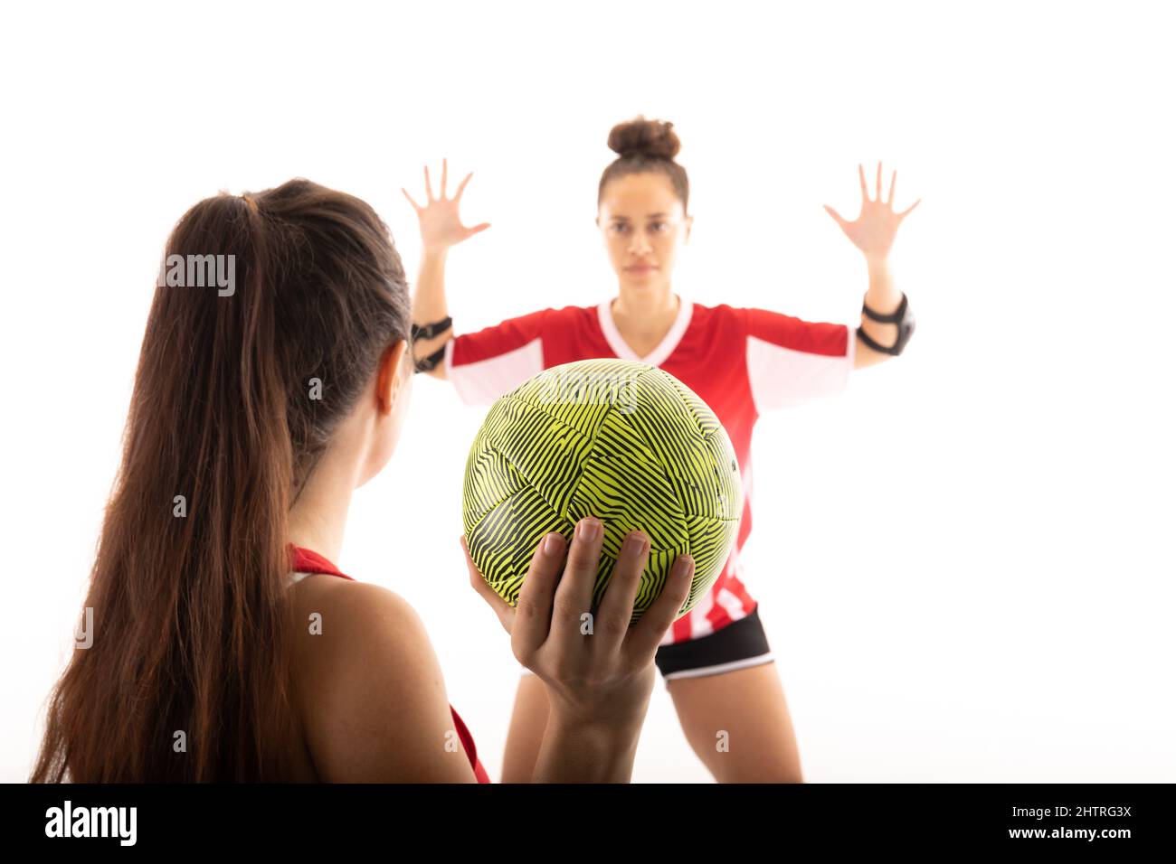 Kaukasische und biraziale junge Handballspielerinnen, die mit Ball vor weißem Hintergrund spielen Stockfoto