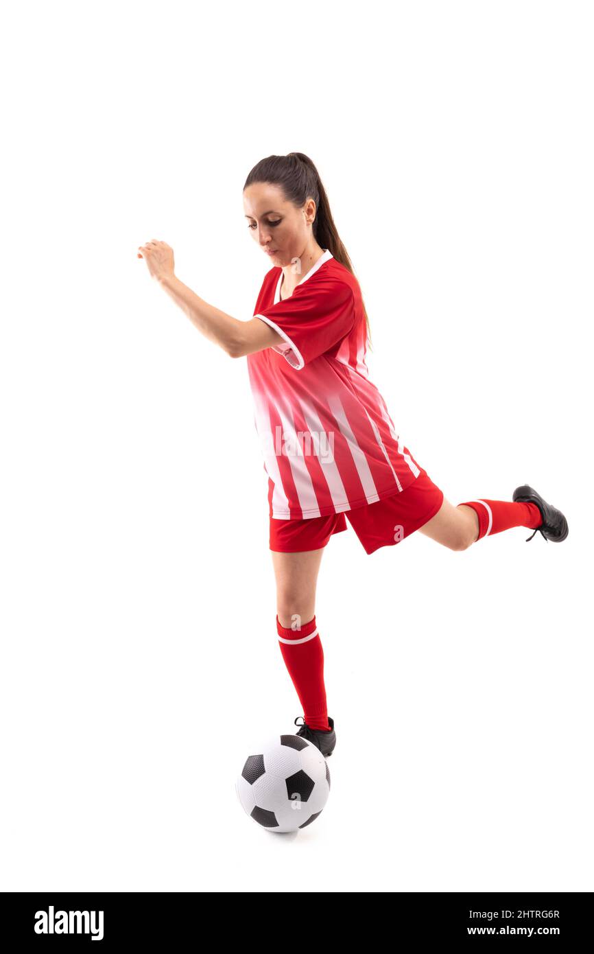 Kaukasische junge Spielerin tritt Fußball, während sie vor weißem Hintergrund Fußball spielt Stockfoto