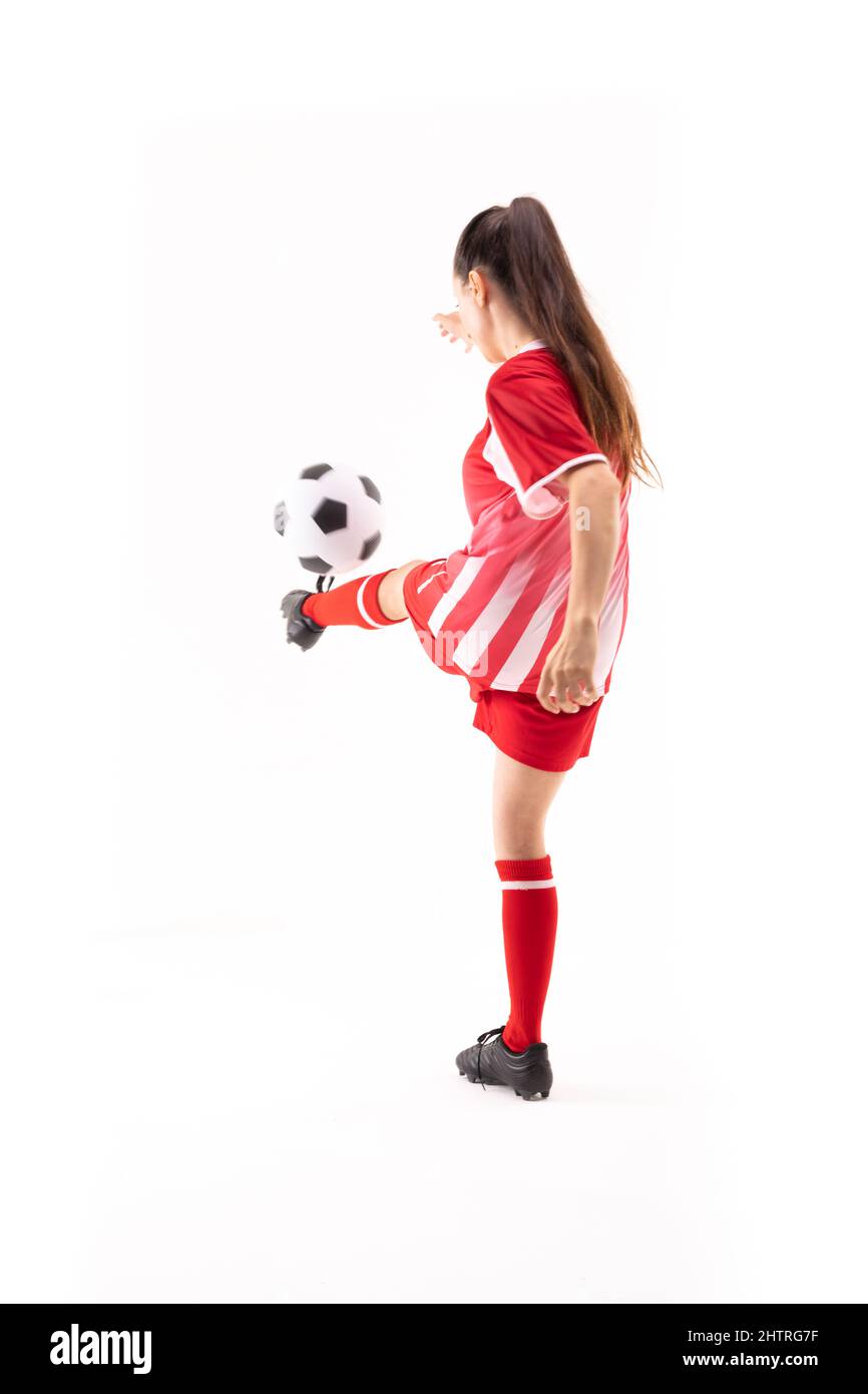 Kaukasische junge Fußballspielerin tritt Fußball vor weißem Hintergrund mit Kopierraum Stockfoto