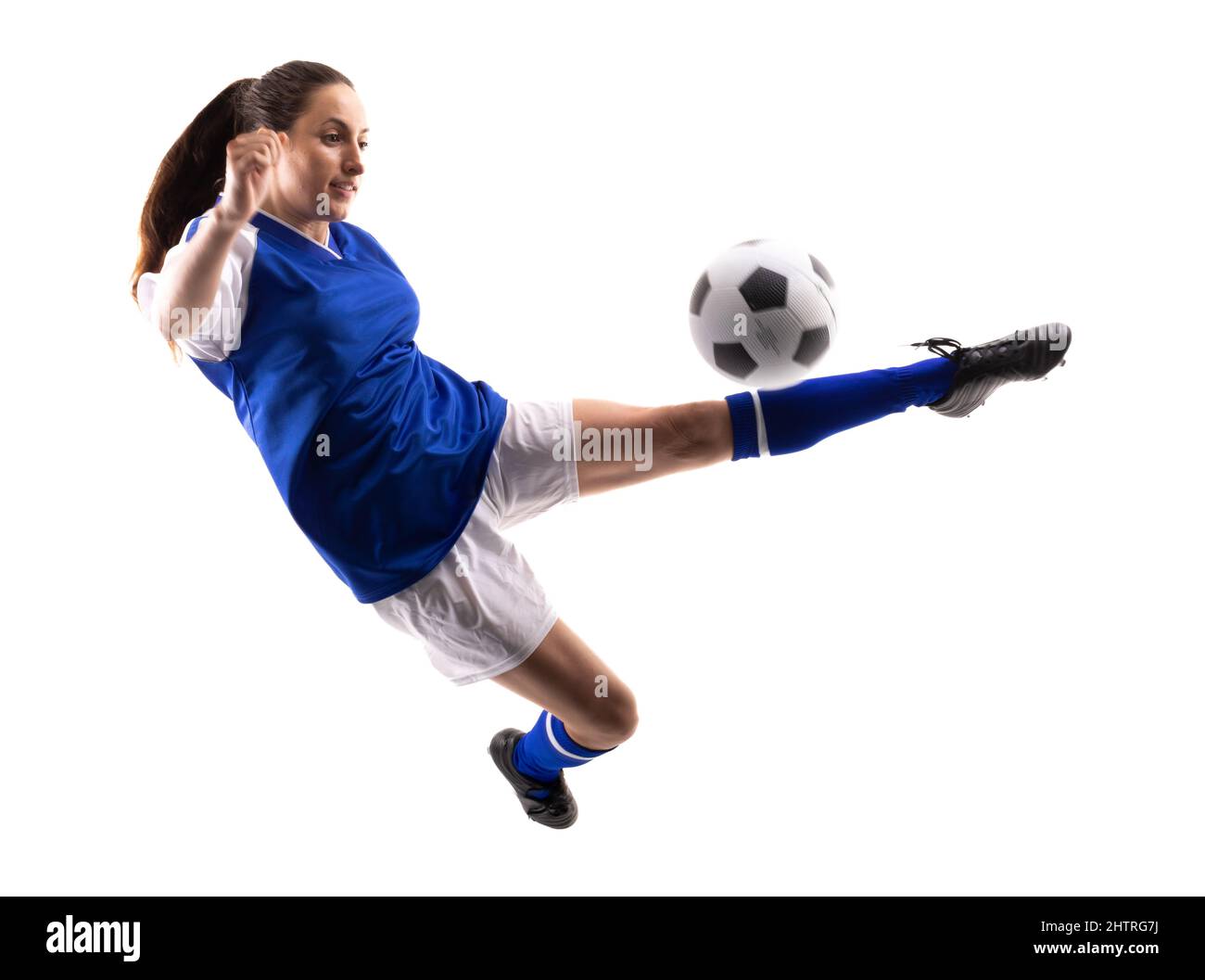 Die ganze Länge der kaukasischen jungen Spielerin in der Luft tritt Fußball während des Fußballs Stockfoto
