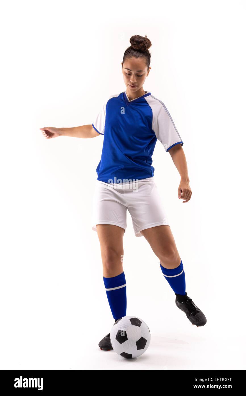 In voller Länge Biracial junge weibliche Fußballspielerin tritt Fußball vor weißem Hintergrund Stockfoto