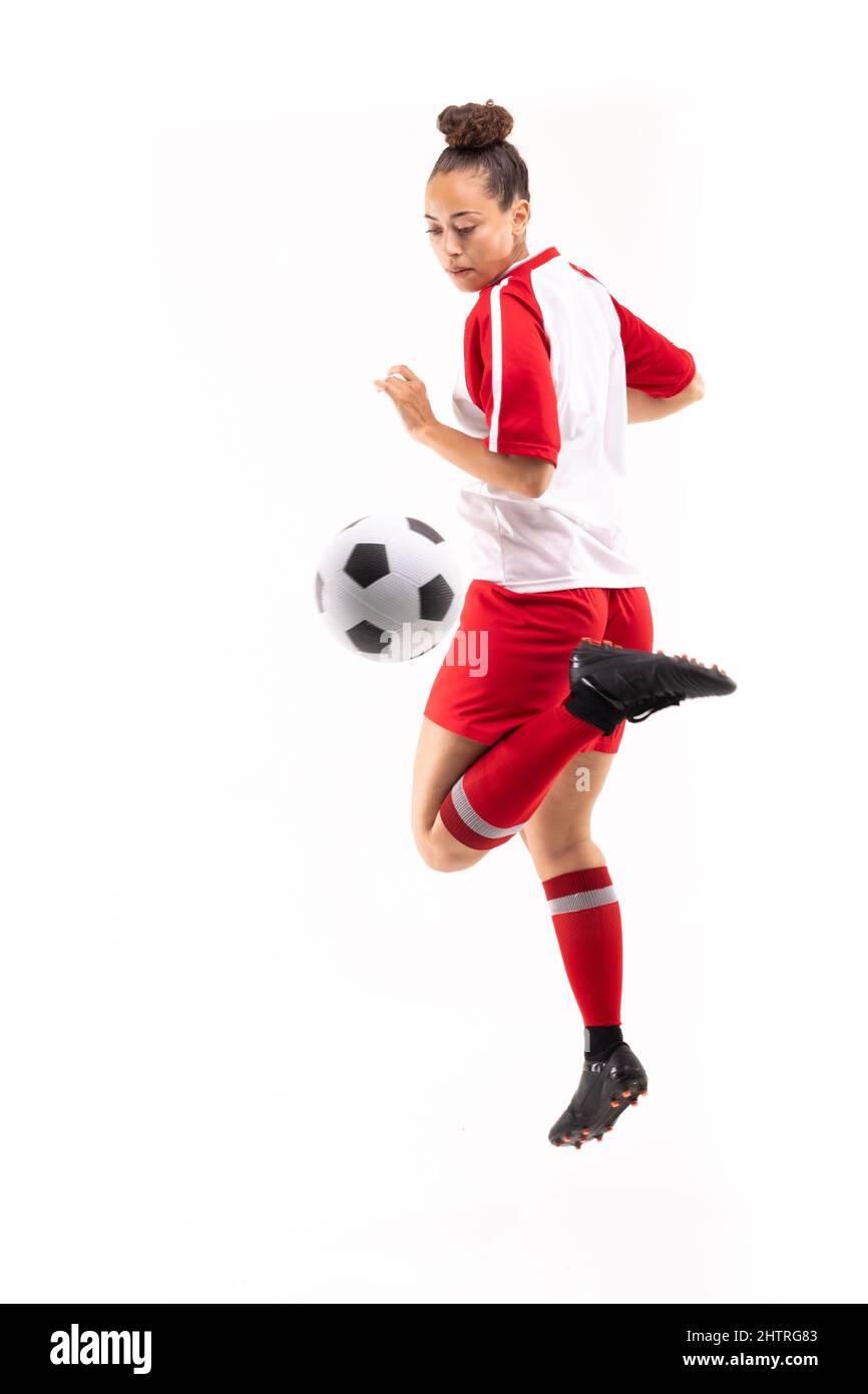 Die gesamte Länge der Biracial junge weibliche Spieler tritt Fußball mit rücker Ferse, während Fußball zu spielen Stockfoto