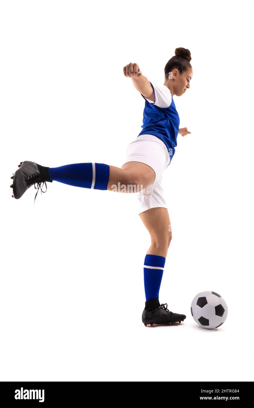 Seitenansicht der biracial jungen Fußballspielerin, die beim Fußballspielen Fußball tritt Stockfoto