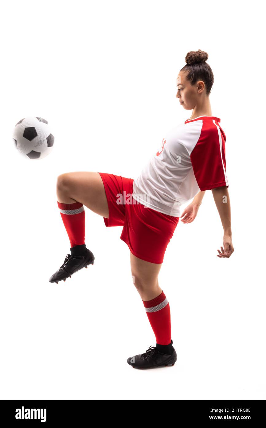 Die gesamte Länge der Biracial junge weibliche Spieler tritt Fußball mit Knie, während Fußball zu spielen Stockfoto