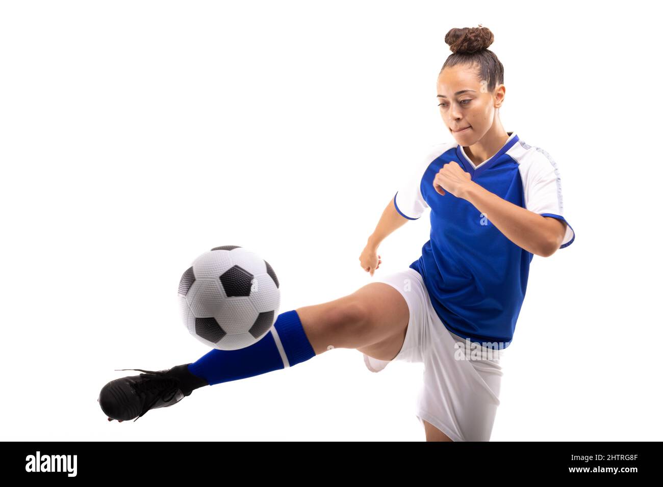 Biracial junge weibliche Spieler tritt Fußball, während Fußball vor weißem Hintergrund Stockfoto