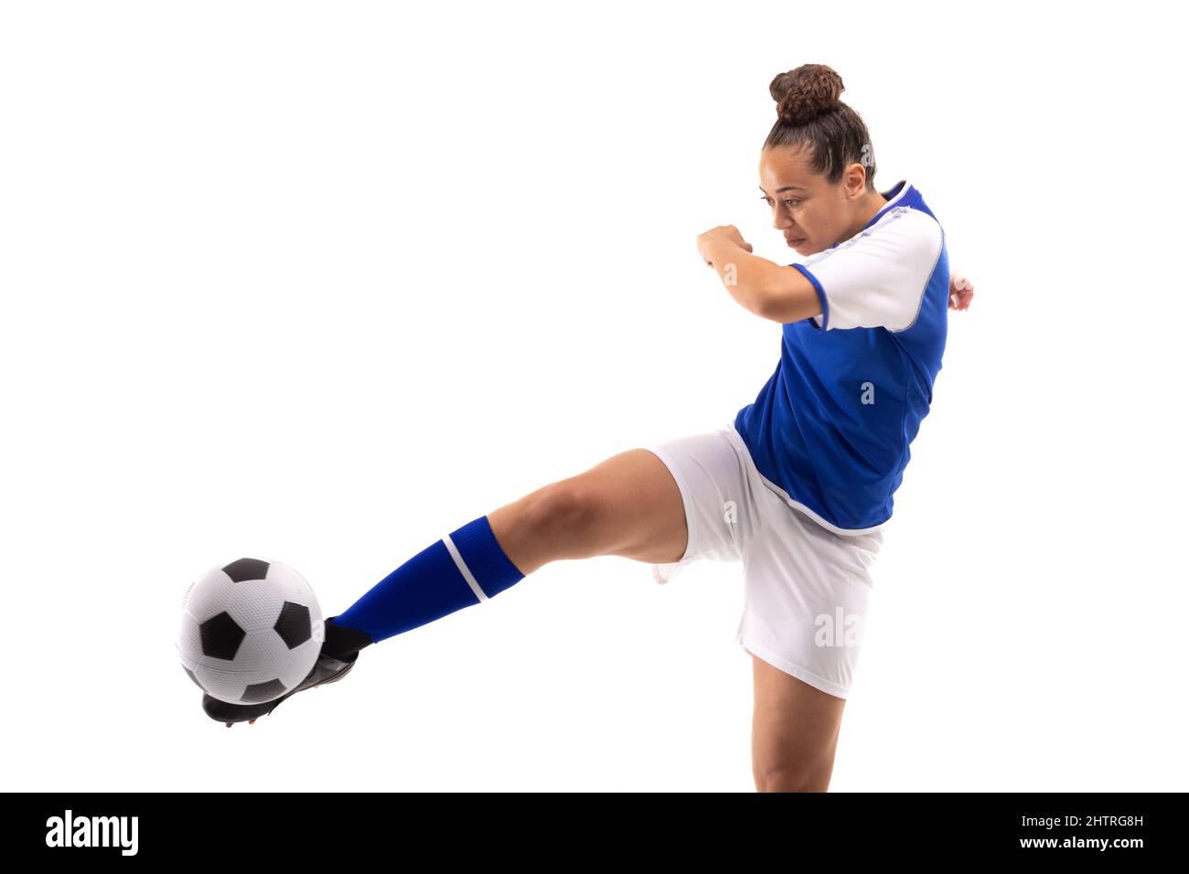 Die gesamte Länge der biracial junge Fußballspielerin tritt Fußball, während sie Fußball spielt Stockfoto