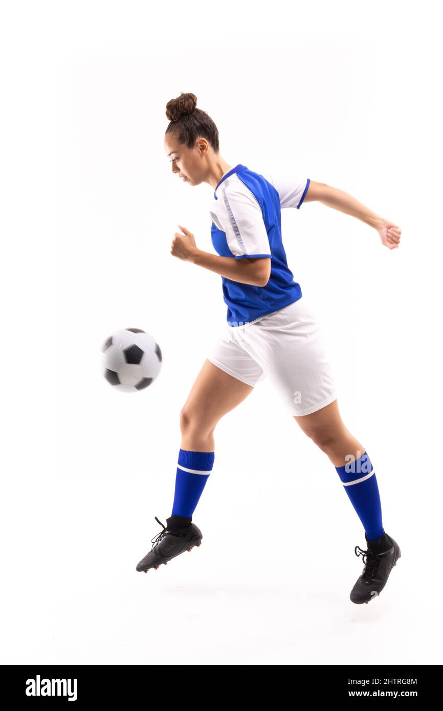 Seitenansicht einer jungen Biracial-Spielerin in der Luft beim Fußballspielen Stockfoto