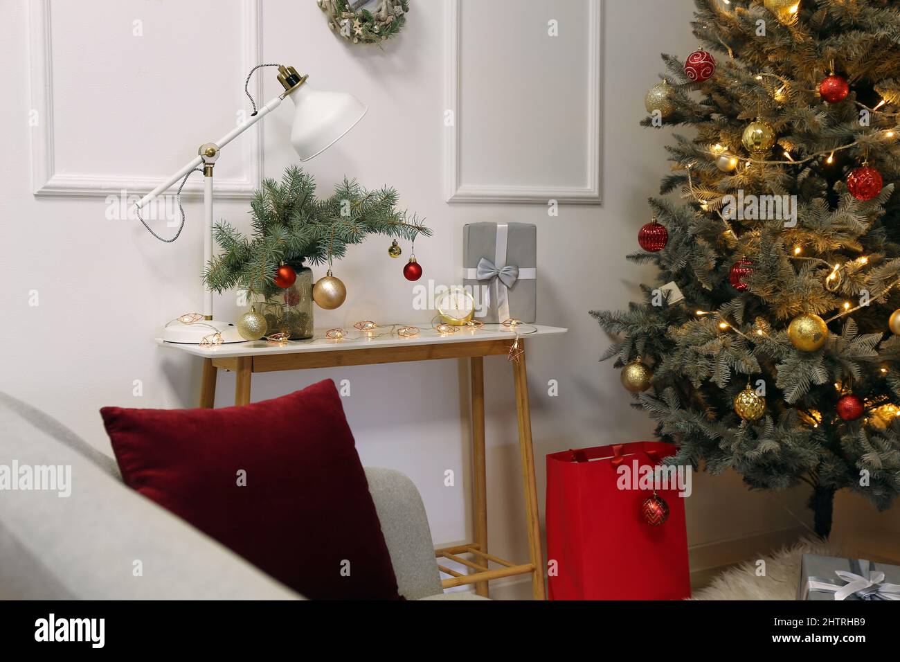 Vase mit Tannenzweigen, Weihnachtskugeln, Lampe und Geschenk auf dem Tisch  im Zimmer Stockfotografie - Alamy