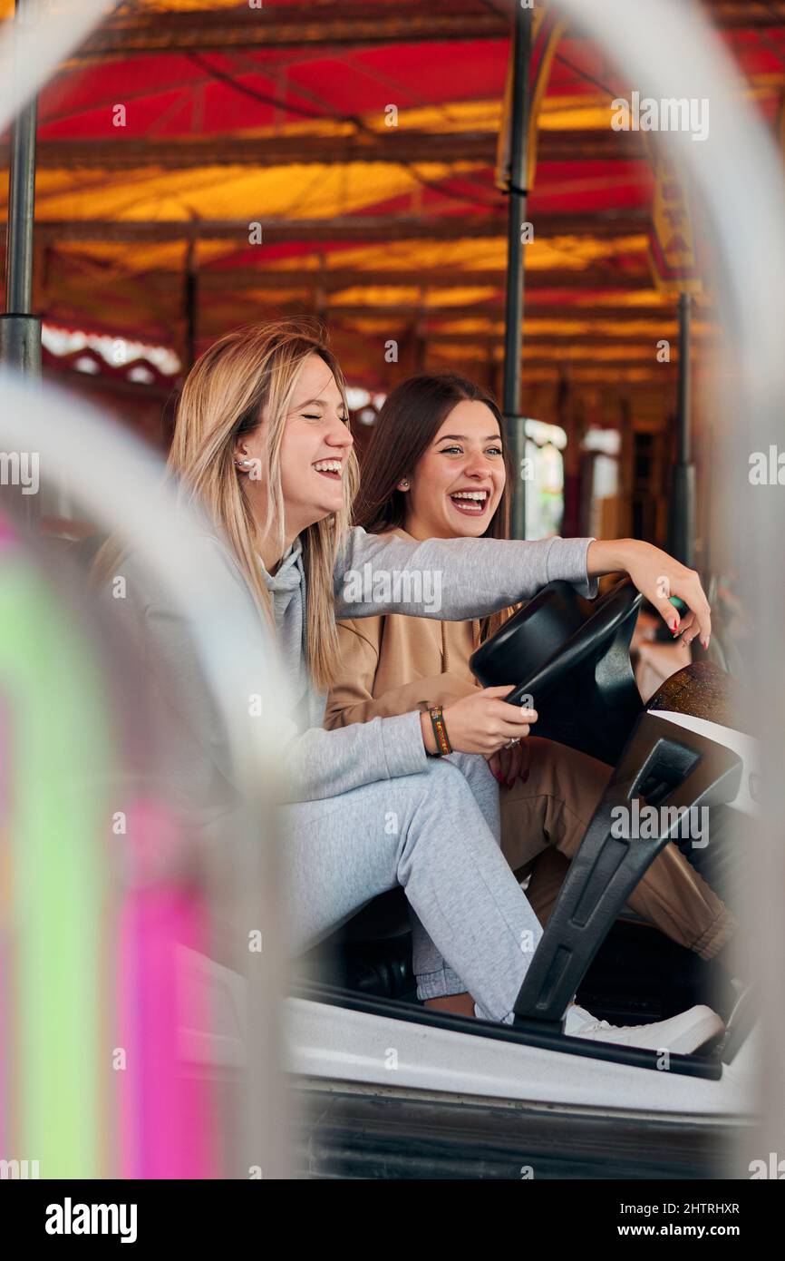 Zwei junge Frauen, die Spaß haben, während sie ein Autoscooter fahren Stockfoto