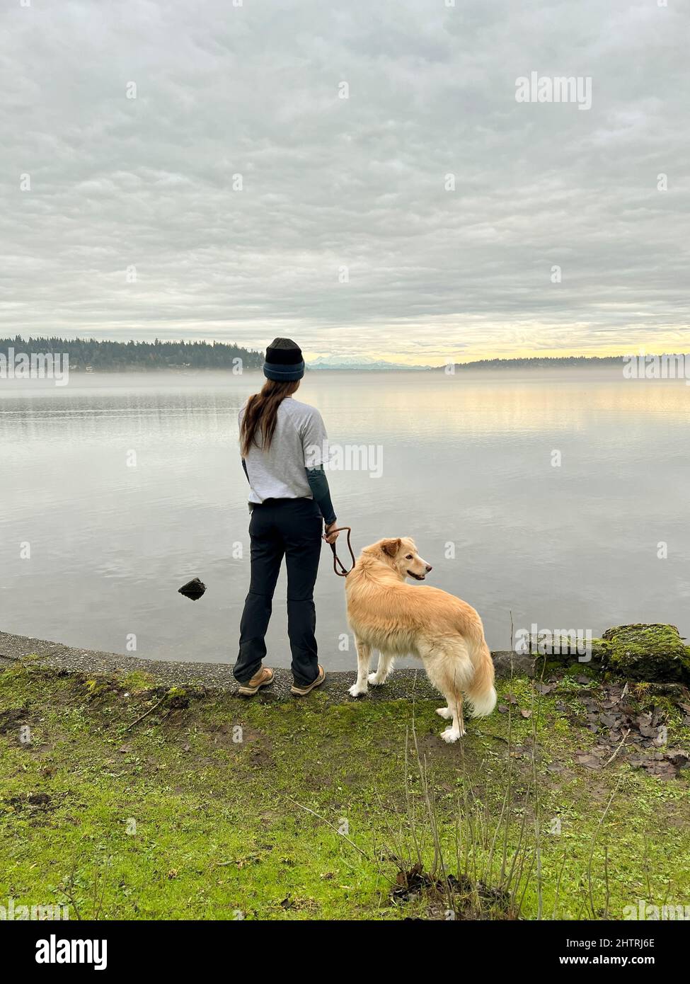 Weibchen posiert mit ihrem Hund im Seward Park in Seattle Stockfoto