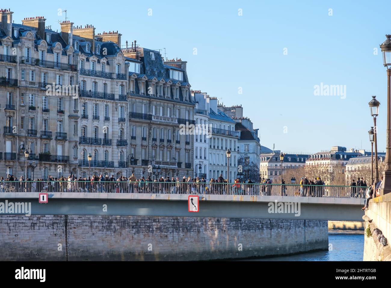 Paris, Frankreich - 27. Februar 2022 : Touristen überqueren eine Brücke am Flusslauf in der Innenstadt von Paris Stockfoto