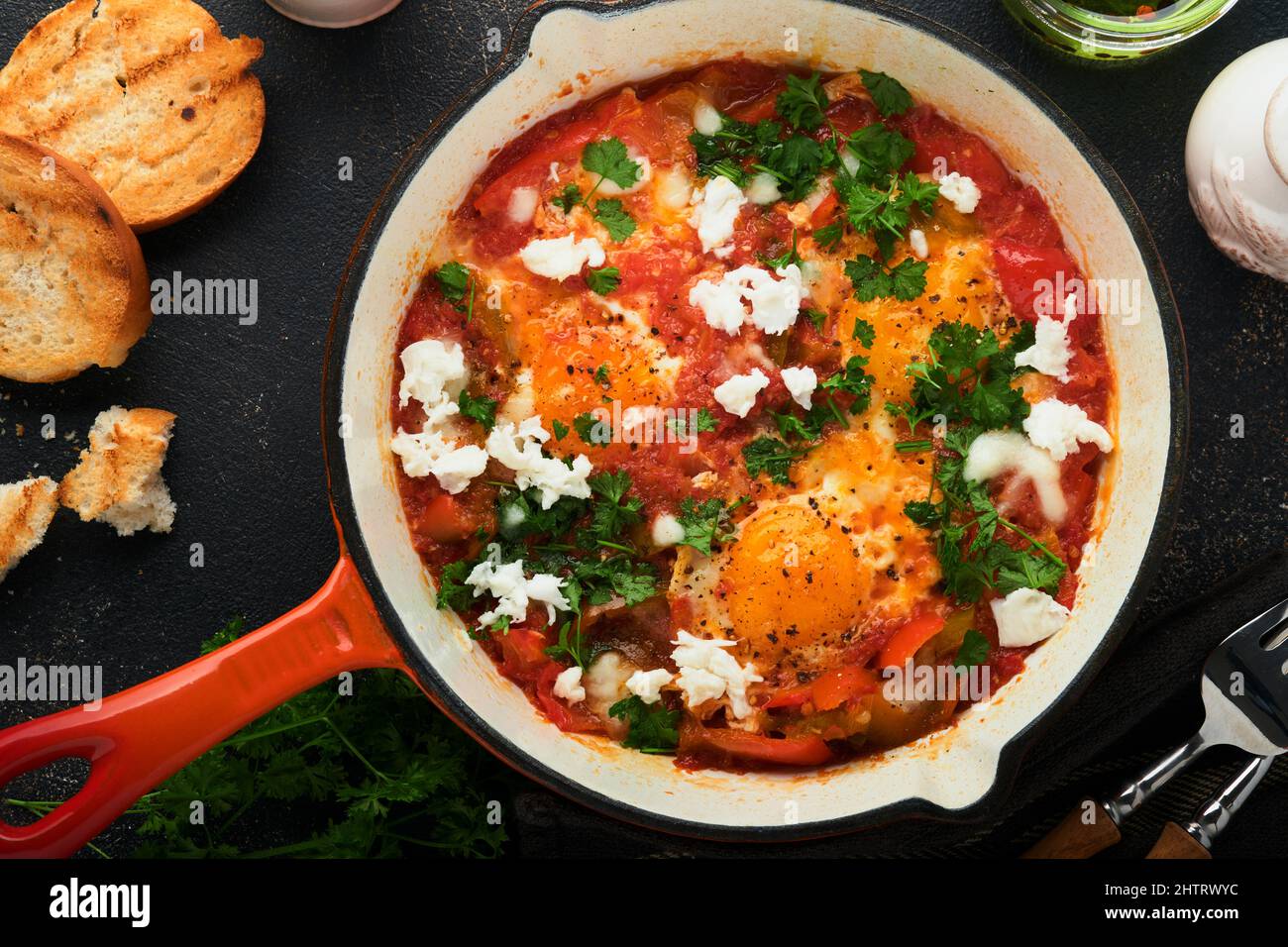 Shakshuka. Hausgemachte Spiegeleier mit Gemüse in eiserner Pfanne auf altem dunklen Schiefer, Stein oder Beton Hintergrund. Traditionelle Küche Israels. Spät Stockfoto