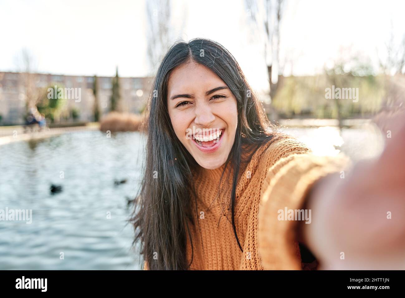 Porträt einer charmanten jungen Frau, die lächelt, während sie ein Selfie-Foto fotografiert. Stockfoto