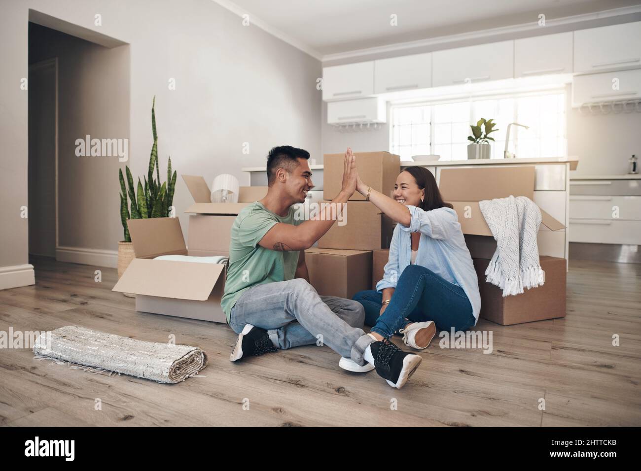 Wir haben uns für dieses Hotel entschieden. Aufnahme eines Paares, das sich ein High-Five teilt, während es in sein neues Zuhause zieht. Stockfoto