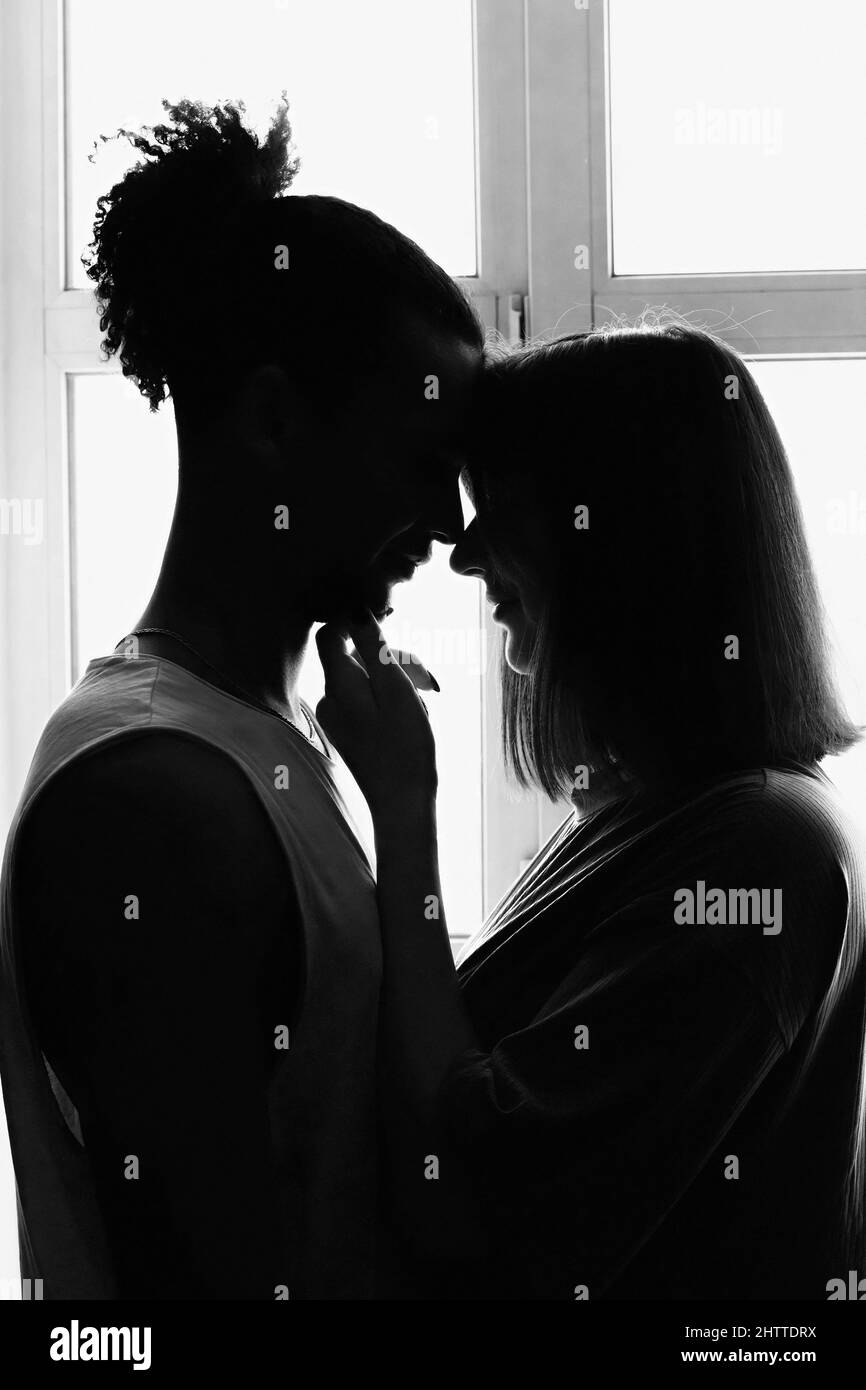 Schwarz-Weiß-Porträt, Silhouette eines multirassischen Paares, Freund und Freundin von Angesicht zu Angesicht, stehen am Fenster Stockfoto