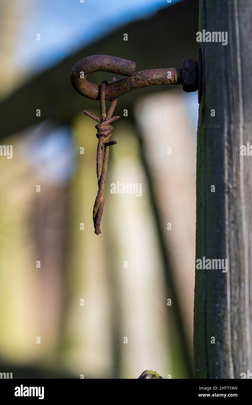 Rostiger Stacheldraht, der am Haken hängt Stockfoto
