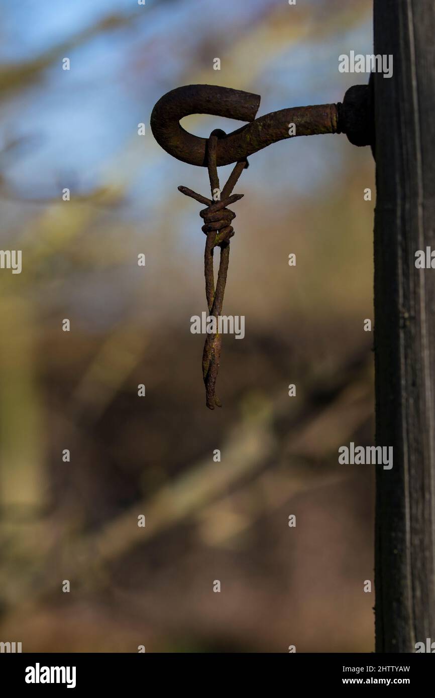 Rostiger Stacheldraht, der am Haken hängt Stockfoto