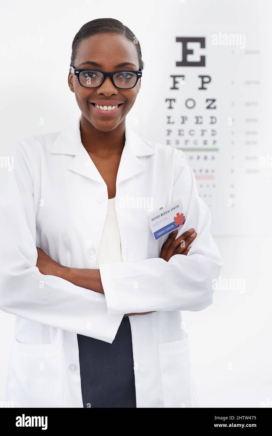 Wie klar können Sie sehen. Porträt einer weiblichen Optometristin, die neben einer Augentestkarte steht. Stockfoto