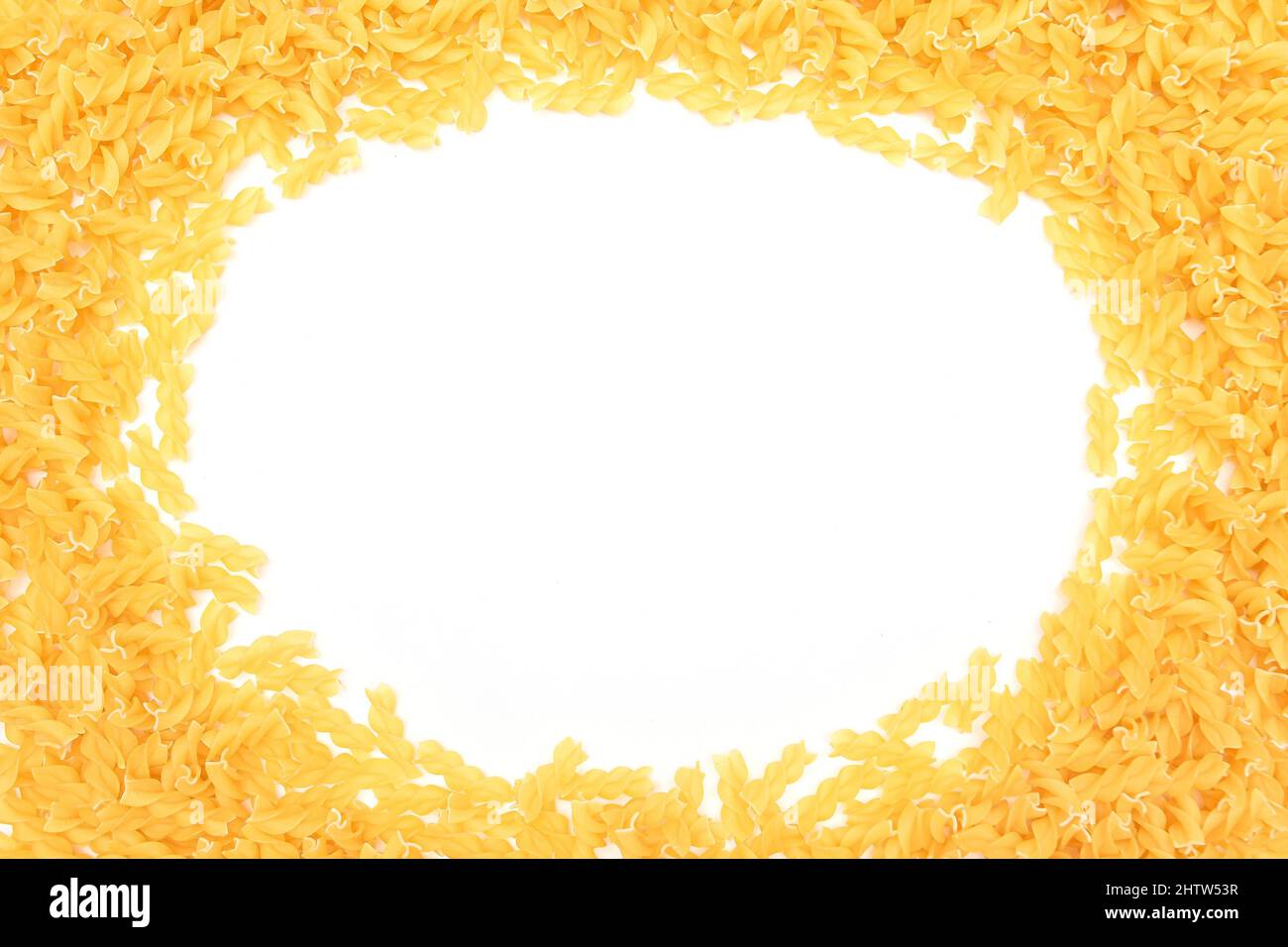 Ein Rahmen aus ungekochter Fusilli Pasta, verstreut auf weißem Tisch - Mock Up. Rohe und trockene Macaroni. Ungesunde und fettarme Lebensmittel. Italienische Kultur Stockfoto