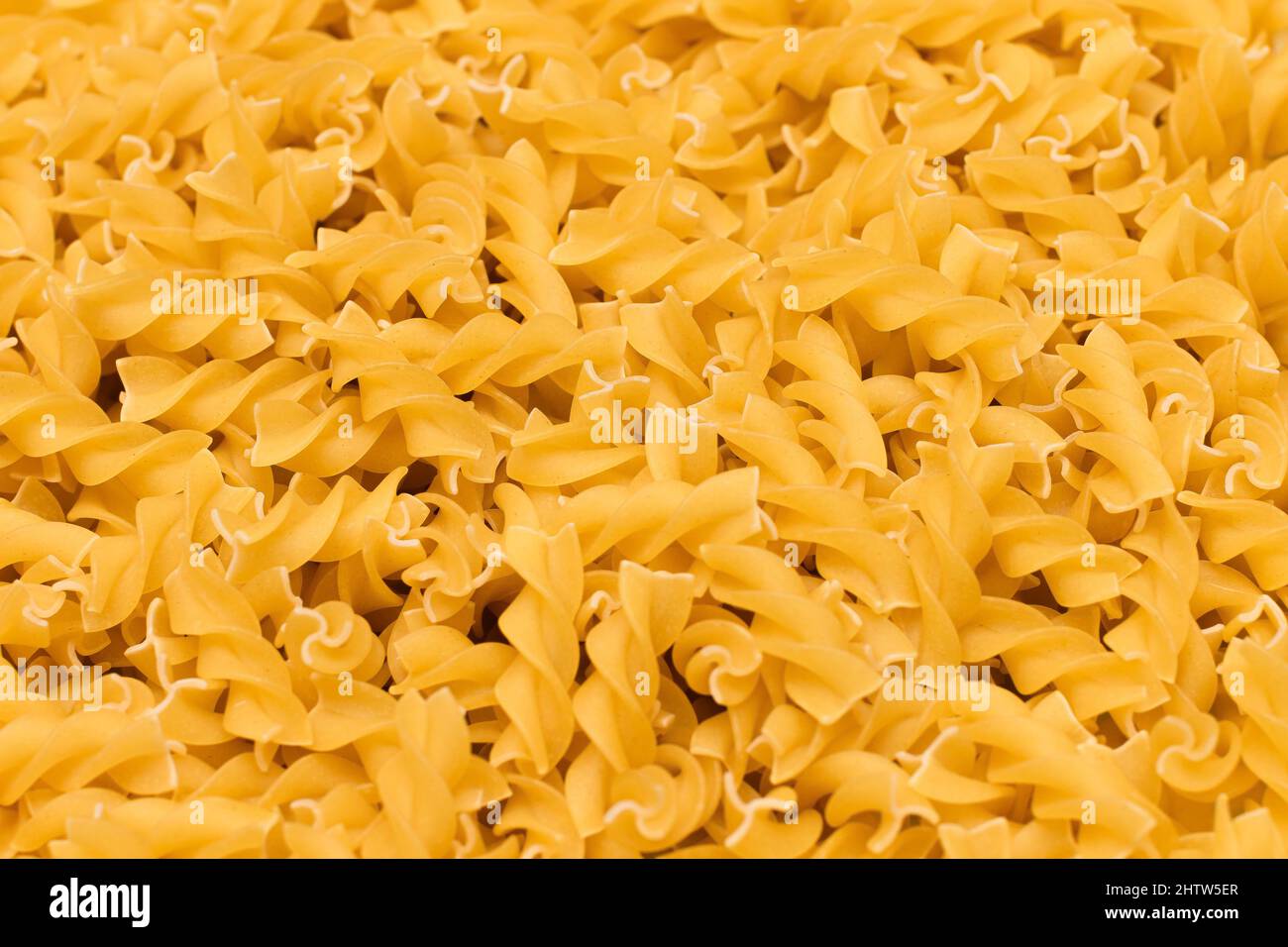 Uncooed Fusilli Pasta - Hintergrund. Textur von hellen Golden Dry Macaroni Stockfoto