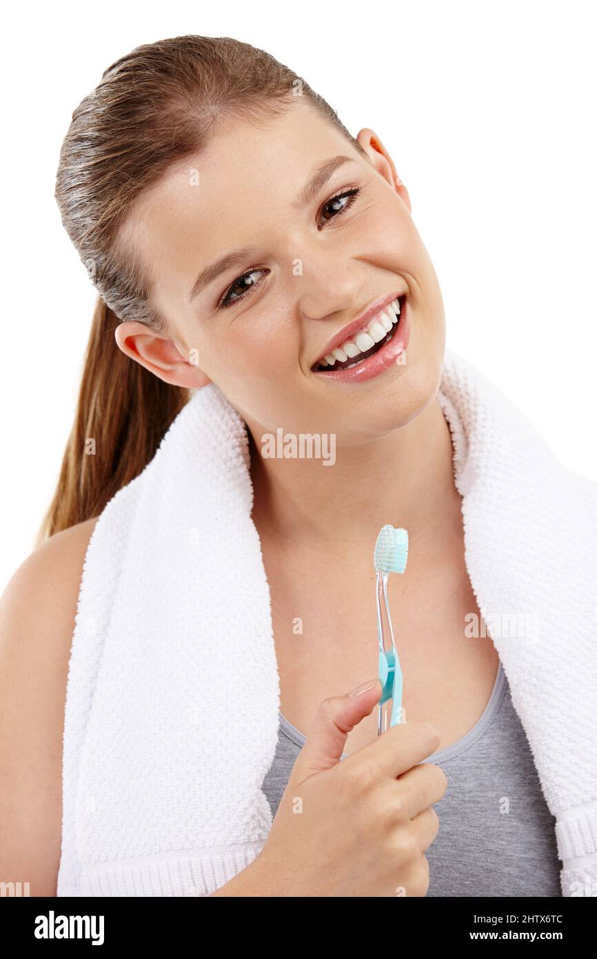 Funkelnde weiße Zähne und ein strahlendes Lächeln. Ein hübsches Mädchen im Teenageralter, das eine Zahnbürste in der Hand hält und lächelt. Stockfoto