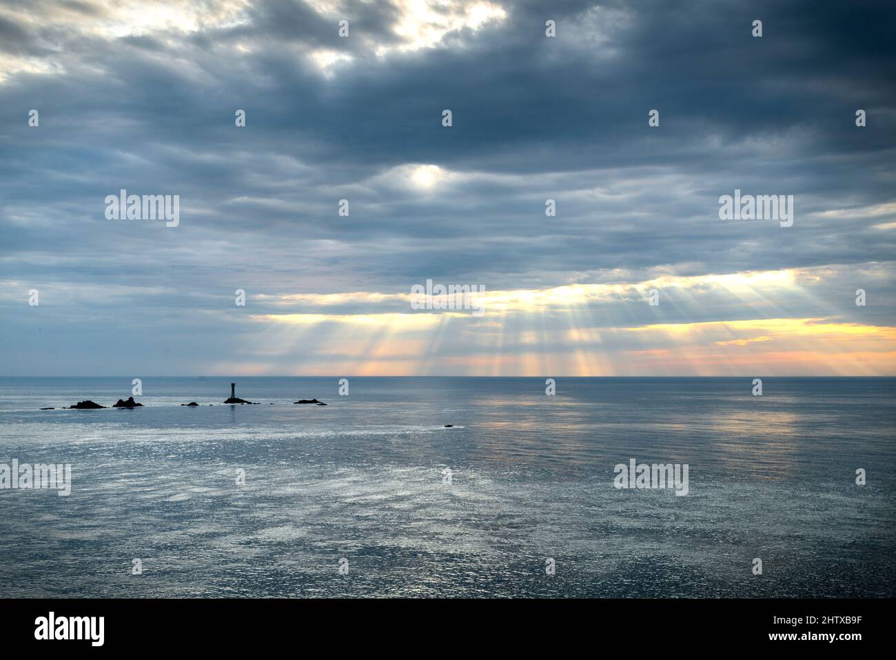 Vom berühmten westlichsten Wahrzeichen Großbritanniens und der Küste Cornis aus gesehen, ist der Leuchtturm von Longships umgeben von einem ruhigen Atlantischen Ozean im Sommer Stockfoto