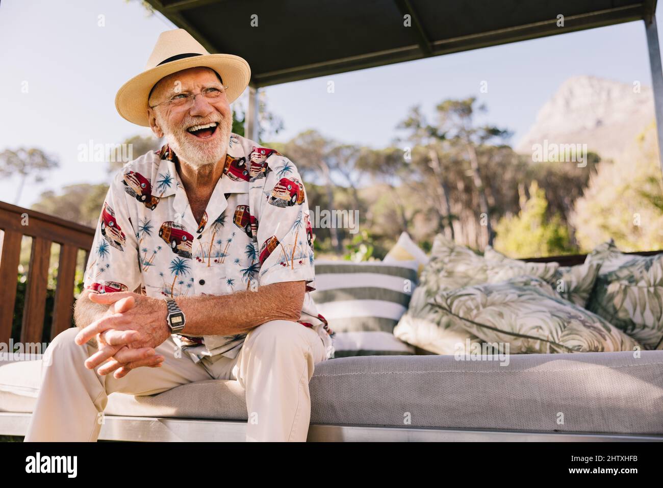 Urlaub nach dem Ruhestand. Glücklicher älterer Mann, der fröhlich lachte, während er sich auf einer Couch in einem luxuriösen Spa-Resort erholte. Sorgloser älterer Mann, der ihn genießt Stockfoto