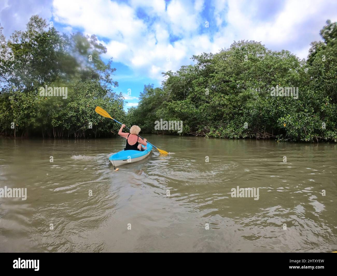 Ältere Frau erkundet den tropischen Regenwald mit dem Kajak Stockfoto