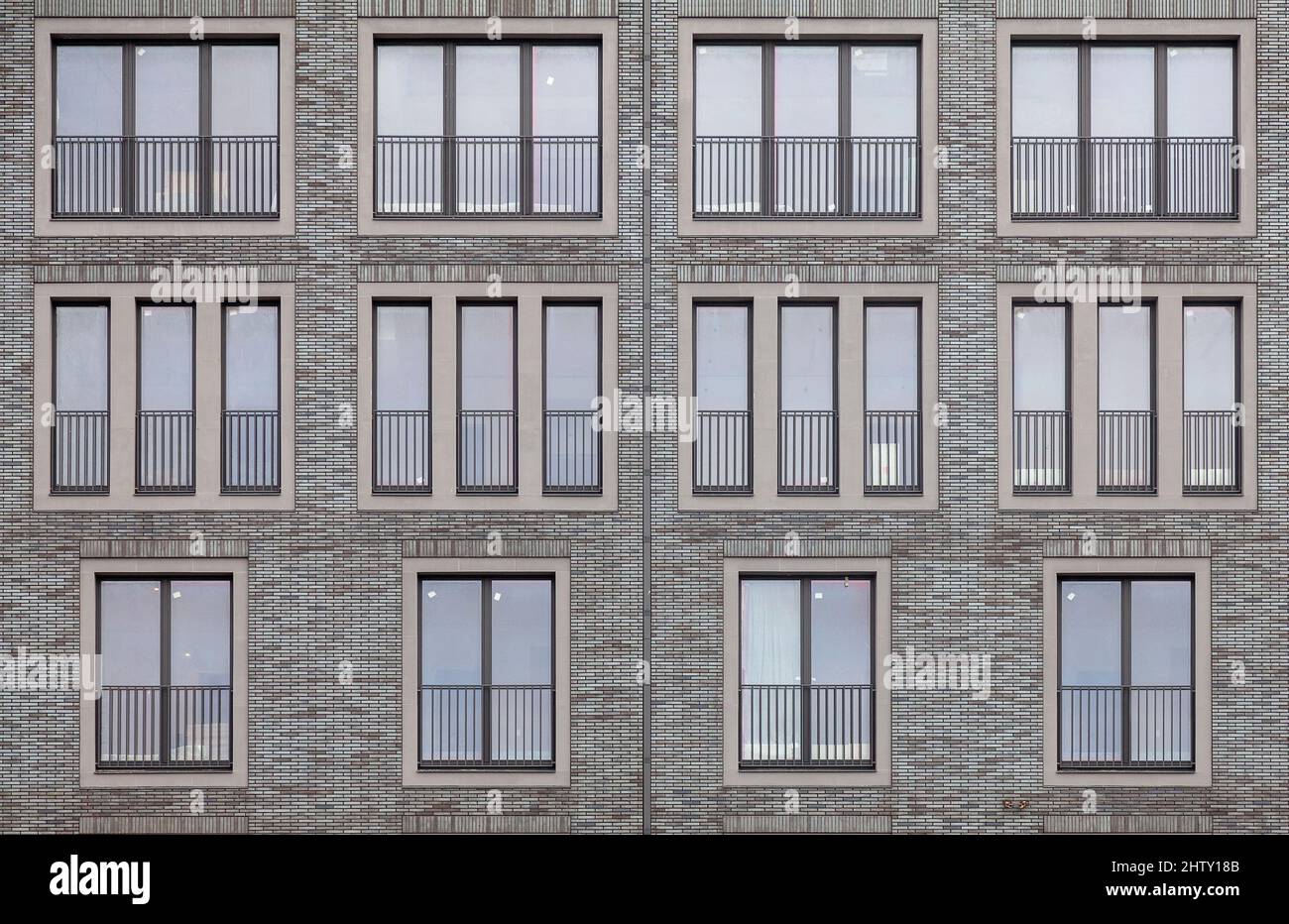 Hintergrundbild - Backsteinmauer eines Gebäudes mit Fenstern verschiedener Größen. Stockfoto