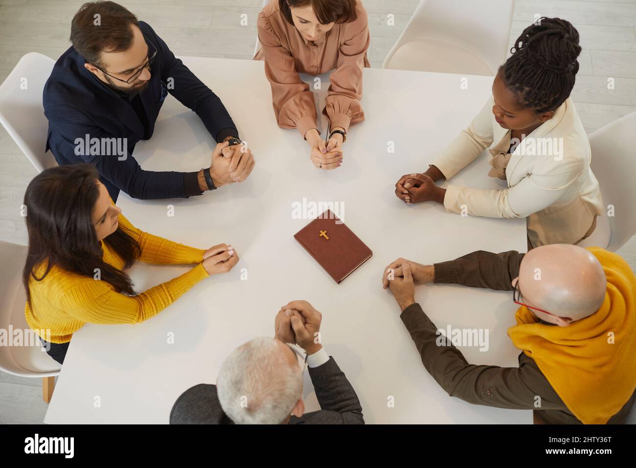 Religiöse Menschen in der Bibelstudiengruppe sitzen am Tisch und beten gemeinsam zu Gott Stockfoto
