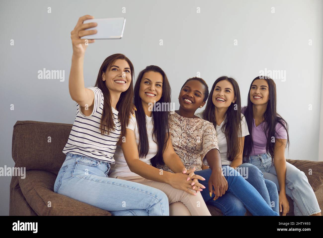 Die besten Freundinnen verschiedener Rassen nehmen zusammen Selfies auf und halten Momente mit der Handykamera fest. Stockfoto