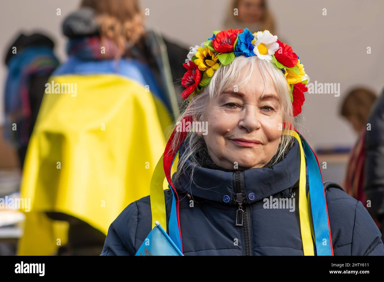 Wunderschöne lächelnde ukrainische Dame mit Blumenkrone während einer friedlichen Demonstration gegen Krieg, Putin und Russland Stockfoto