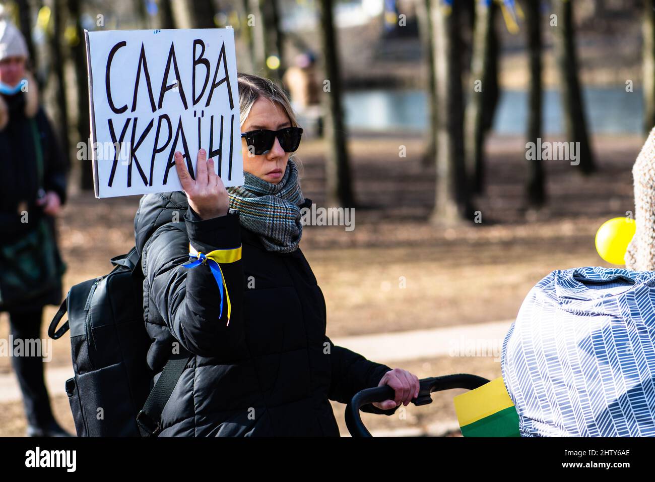 Mädchen mit Kinderwagen während einer friedlichen Demonstration gegen den Krieg, Putin und Russland zur Unterstützung der Ukraine, mit Menschen, Plakaten und Fahnen. Beenden Sie Den Krieg Stockfoto