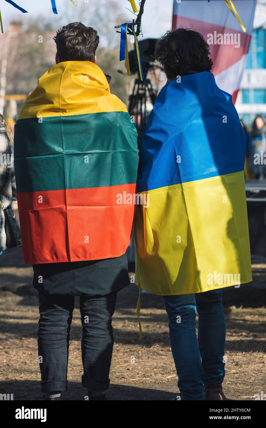 Ein paar Freunde während einer friedlichen Demonstration gegen den Krieg, Putin und Russland zur Unterstützung der Ukraine, mit ukrainischen und litauischen Fahnen Stockfoto