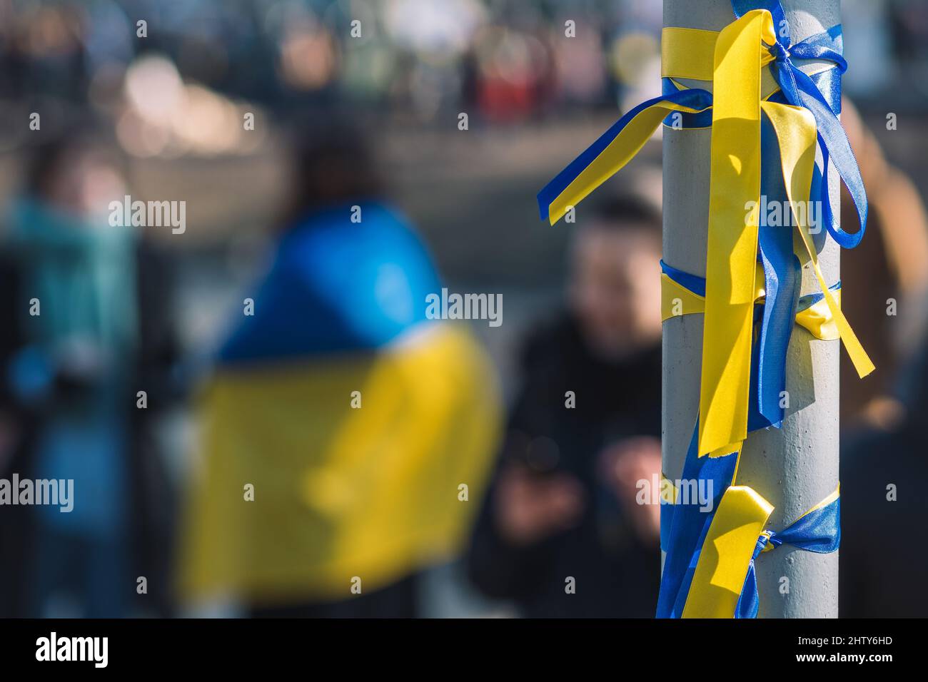 Bänder mit Farben der Ukraine während einer friedlichen Demonstration gegen den Krieg, Putin und Russland, mit ukrainischer Flagge auf dem Hintergrund Stockfoto