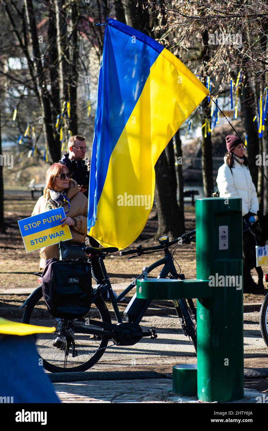 Mädchen während einer friedlichen Demonstration gegen den Krieg, Putin und Russland zur Unterstützung der Ukraine, mit Plakat zeigt Putin als Verbrecher und Flaggen Stockfoto