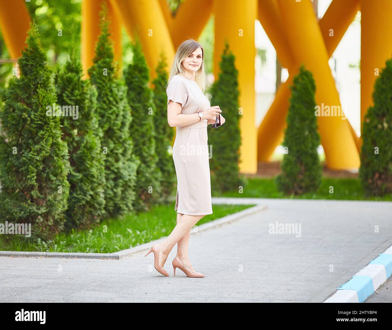 Außenportrait einer jungen schönen Dame, die auf der Straße läuft. Modell in stilvollem Sommerkleid. Weibliches Modekonzept. Lifestyle in der Stadt. Sonniger Tag Stockfoto