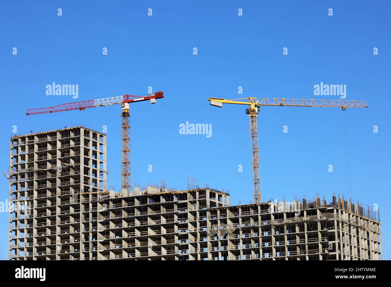 Bau Turmdrehkrane über unfertigen Wohngebäude auf blauem Himmel Hintergrund. Wohnungsbau, Wohnblock Stockfoto