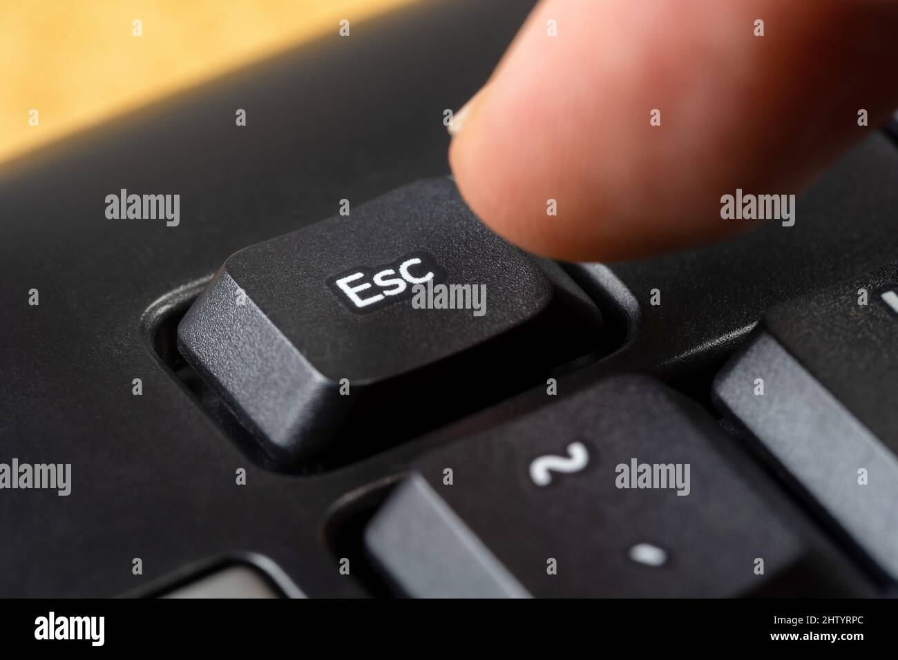 Mann drückt die Escape-Taste auf einer einfachen schwarzen Office-Tastatur, Finger drückt die esc-Taste, Objekt-Makro, extreme Nahaufnahme, Detail. Flucht, sto Stockfoto