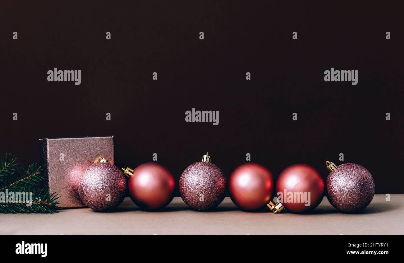Pinke weihnachtskugeln an der braunen und beigen Wand. Elegante Weihnachtsdekoration Hintergrund. Minimal trendige Grußkarte. Frohe weihnachten und ein glückliches neues Ja Stockfoto