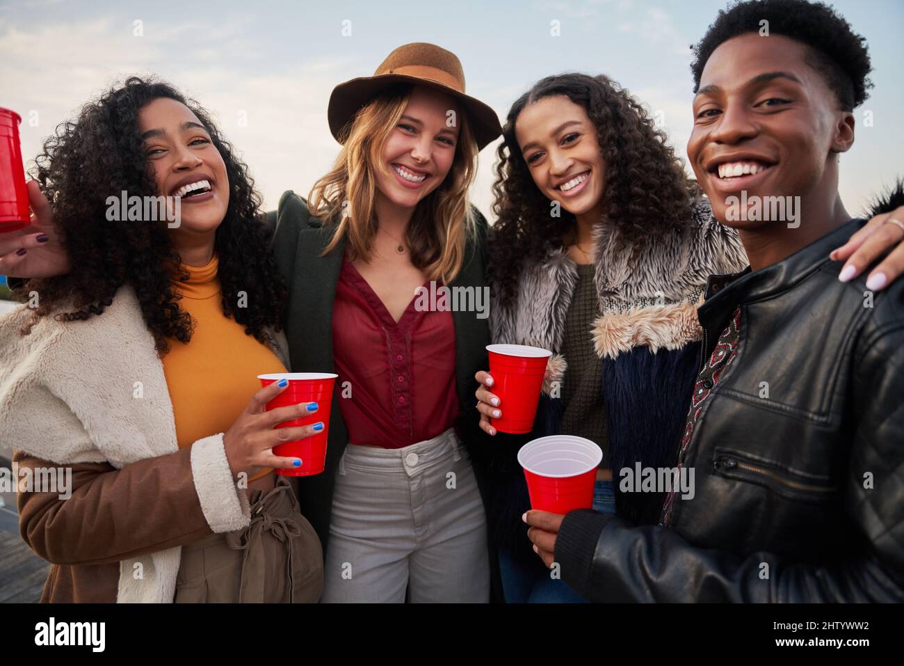Porträt einer stilvollen, vielfältigen Gruppe von Freunden, die vor der Kamera lächeln. Auf der Dachterrasse lachend und gesellig. Stockfoto