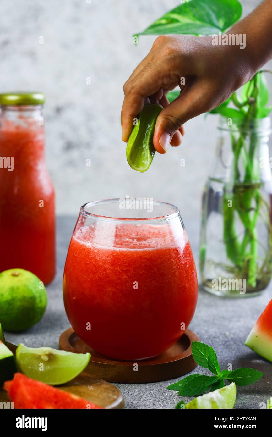 Jus Semangka oder Wassermelonensaft, geschnitten auf Holzschneidebrett mit Scheiben Wassermelone und Limette. Gesundes Getränk während der Sommerferien. Stockfoto