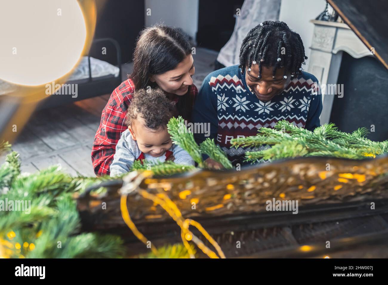 Schöne multirassische Familie feiert Weihnachten, sitzen am Klavier mit ihrem entzückenden Kleinkind Jungen. Hochwertige Fotos Stockfoto