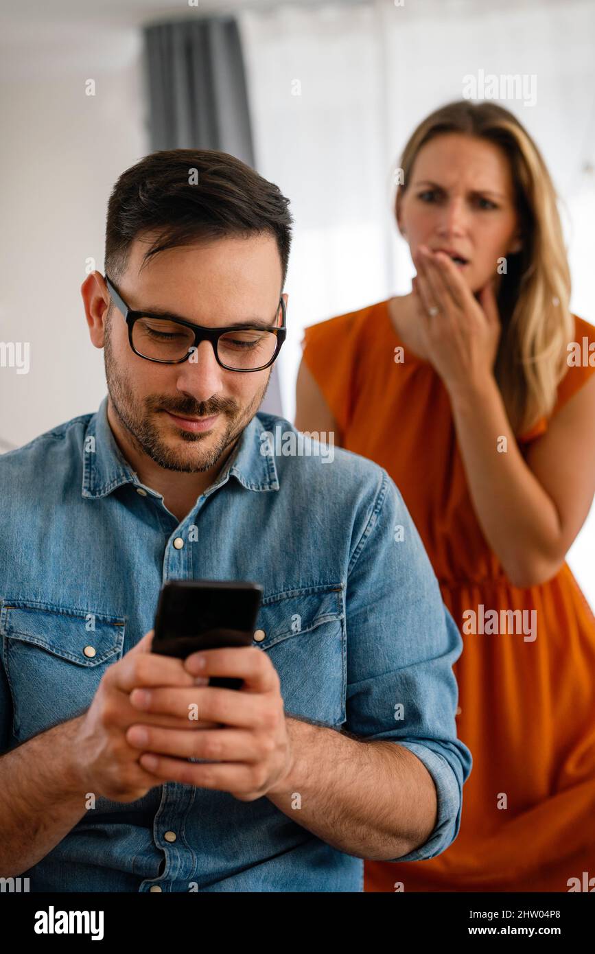 Junges Paar mit Smartphone mit Streit und Ehekonflikt wegen Betrug Stockfoto