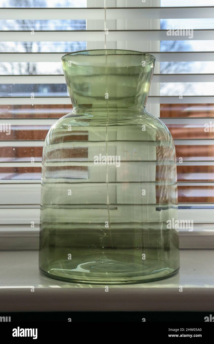 Grüne Vase auf der Fensterbank mit offenen jalousien Stockfoto