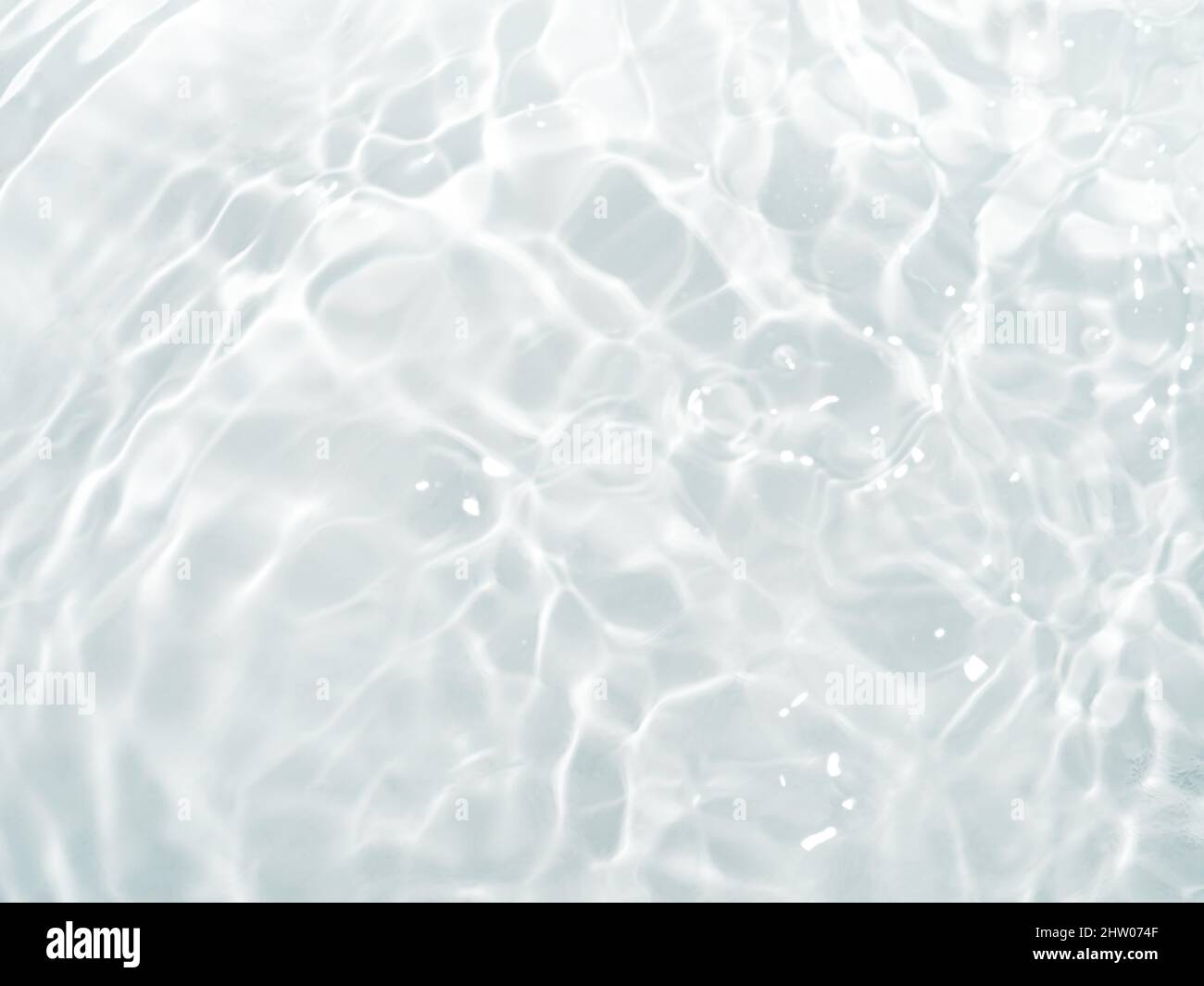 Verschwommenes Wellenwasser auf weißem Hintergrund. Schatten des Wassers auf Sonnenlicht. Modell für Produkt-, Spa- oder Reisehintergrund. Marmor Wasseroberfläche als Hintergrund Tapete Stockfoto