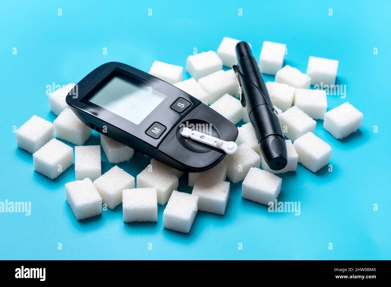 Glucometer, Zuckerwürfel auf blauem Hintergrund hohes Blutzucker- und Diabetes-Konzept Draufsicht Flat Lay 14. November - Weltdiabetestag. Stockfoto