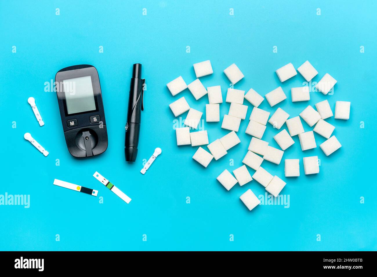 Glucometer, Zuckerwürfel auf blauem Hintergrund hohes Blutzucker- und Diabetes-Konzept Draufsicht Flat Lay 14. November - Weltdiabetestag. Stockfoto