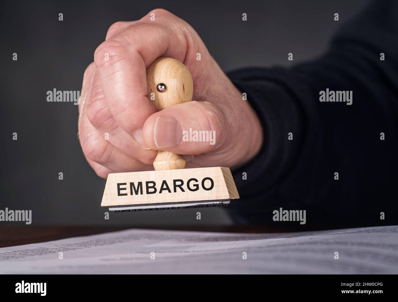 Hand mit Stempel und Inschrift Embargo stempelt ein Dokument Stockfoto